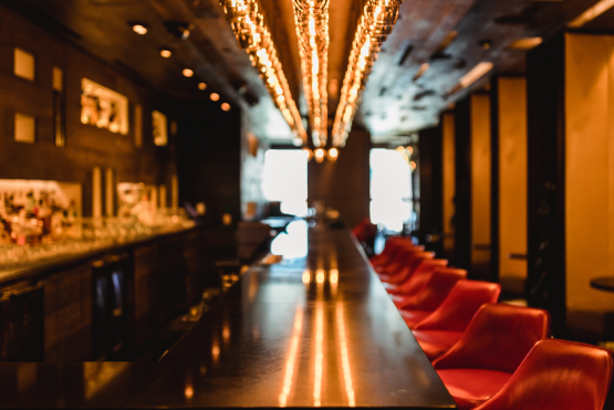 Modern bar with red stools and warm ambient lighting