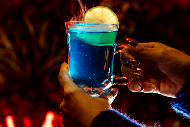 A vibrant blue cocktail with lemon garnish